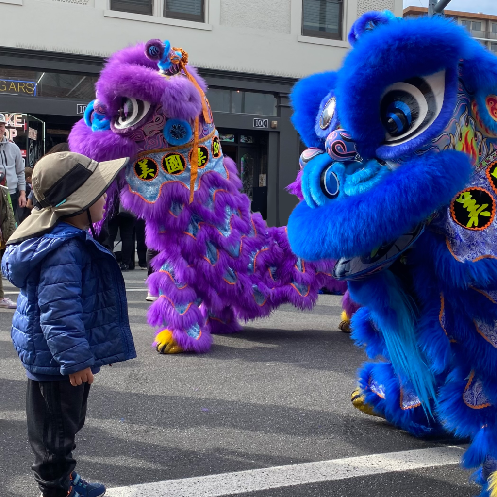 Photo of a child and a blue lion dancer looking at each other