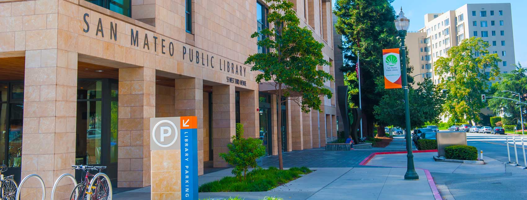 Photo of a brick building with a sign that says San Mateo Public Library