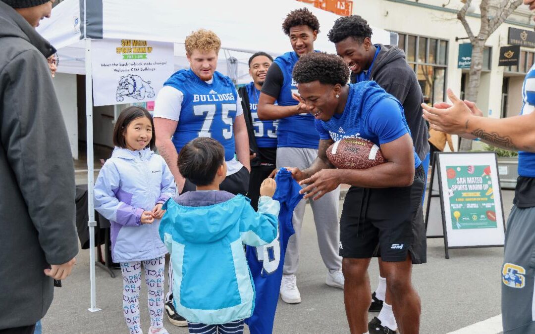 Photo of college football players meeting two kids