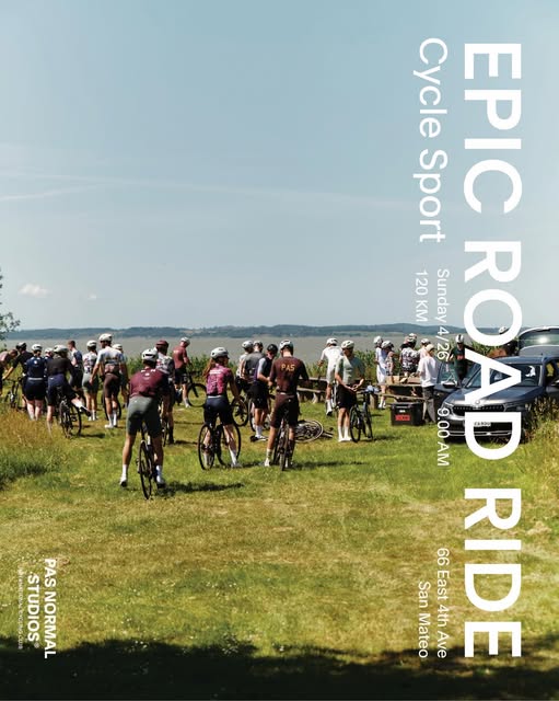 photo of a large group of people standing still with bicycles overlooking a scenic view with a blue sky