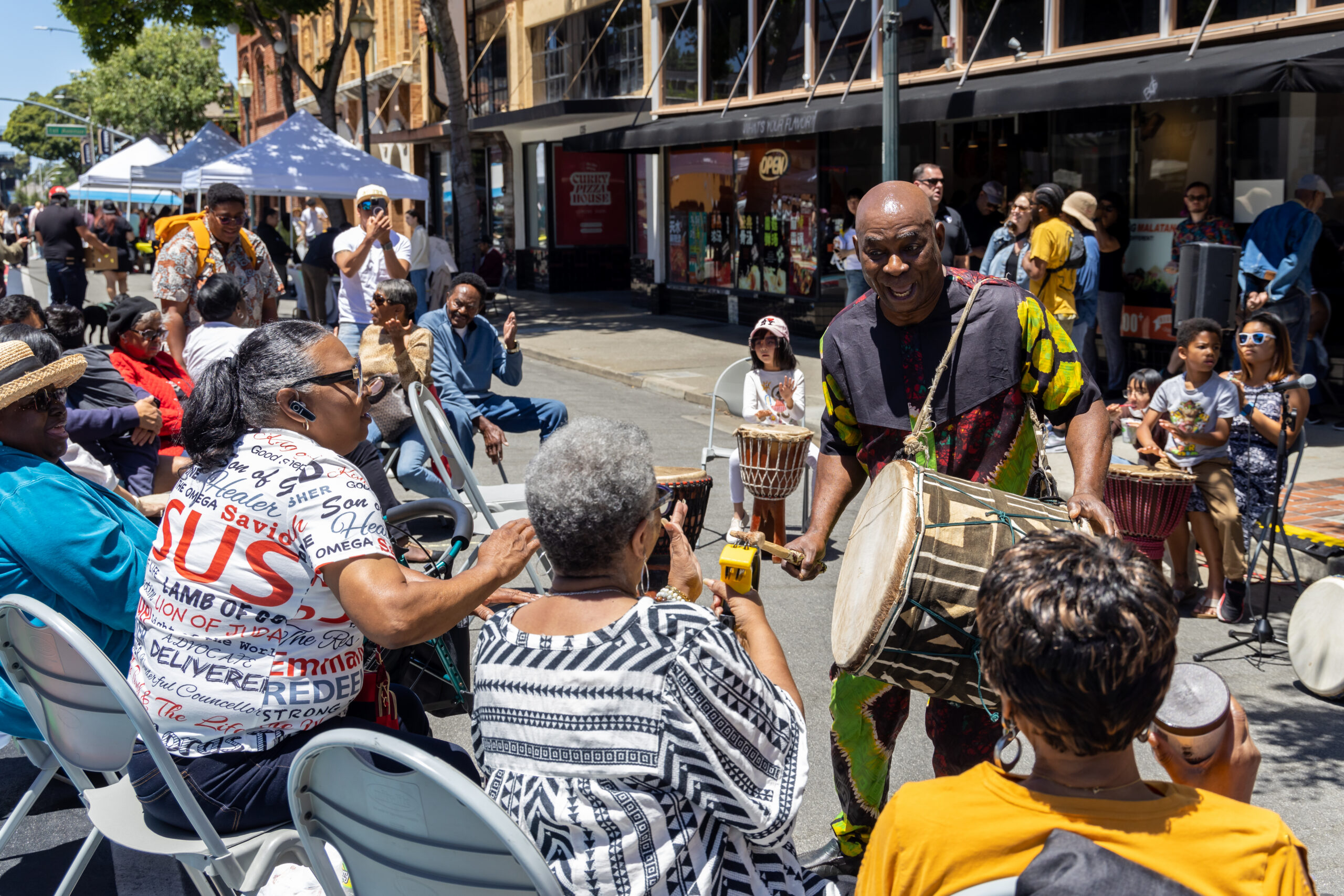 photo of a drummer in African clothing interacting with an outdoor drum circle