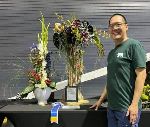 Photo of the teacher with two floral arrangements